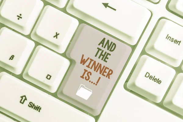 Handstilstext och vinnaren är. Begreppet innebär att tillkännage vem som fick första plats vid tävling eller examen Vit dator tangentbord med tom anteckning papper ovanför vit bakgrund nyckel kopiera utrymme. — Stockfoto