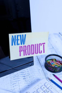 Yeni Ürün yazma el yazısı metin. Özellikleri farklı mal ve hizmetler anlamına gelen kavram Klavye ve sabit yakınında siyah bilgisayar ekranına bantlanmış Not kağıdı.