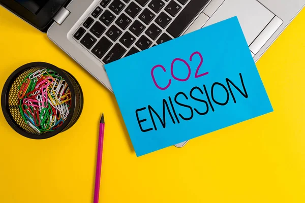 Kelime yazma metni CO2 emisyonu. Zamanla sera gazlarının atmosfere salınması için iş kavramı metalik dizüstü bilgisayar küçük kağıt kalem ataçları renkli arka plan. — Stok fotoğraf