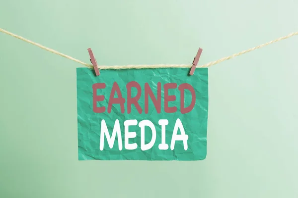 Writing note showing Earned Media. Business photo showcasing Publicity gained through promotional efforts by multimedia Clothesline clothespin rectangle shaped paper reminder white wood desk.