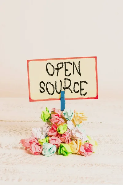 Writing note showing Open Source. Business photo showcasing denoting software which original source code freely available Reminder pile colored crumpled paper clothespin wooden space.