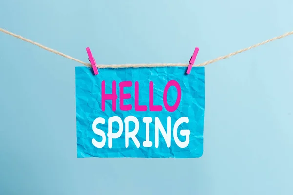 Pisanie notatki pokazano Hello Spring. Business Photo gablota powitanie sezonu po zimie kwitnących kwiatów garderoba clothespin prostokąt kształt papieru przypomnienie biały drewniany biurko. — Zdjęcie stockowe