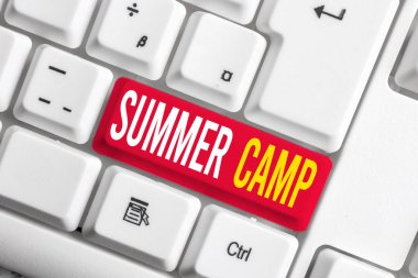 Yaz Kampı'nı yazan el yazısı metin. Kavram yaz aylarında çocuklar ve gençler için Denetimli program anlamına gelir. Beyaz bilgisayar klavyesi üzerinde boş not kağıdı ile beyaz arka plan tuşu kopyalama alanı.