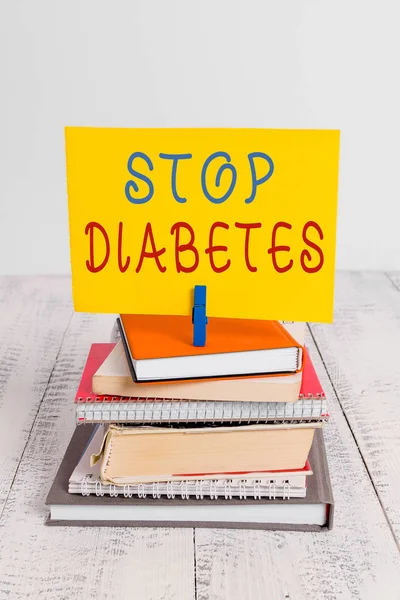 Conceptual hand writing showing Stop Diabetes. Business photo showcasing Blood Sugar Level is higher than normal Inject Insulin pile stacked books notebook pin color reminder white wooden.