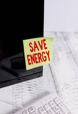 Kelime yazma metni Enerji tasarrufu. Beyaz klavyenin yanındaki siyah bilgisayar monitör ekranına bantlanmış benzer bir sonuç elde etmek için kullanılan güç miktarını azaltmak için iş konsepti.