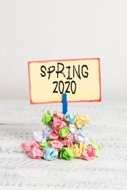 İlkbahar 2020'yi gösteren bir not. Kış mevsiminin ardından çiçeklerin yükseldiği yılın iş fotoğrafı sergileyen kazık renkli buruşuk kağıt clothespin ahşap alan.