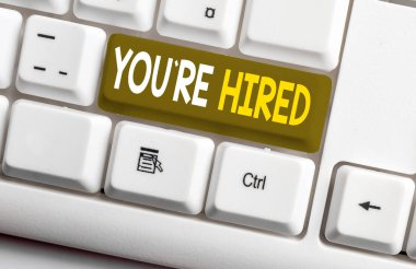 Kavramsal el yazısı You Re Hired gösteren. İş fotoğraf metin Yeni İş İstihdam Newbie Kayıtlı Kabul İşe Beyaz pc klavye beyaz arka plan üzerinde not kağıdı ile.