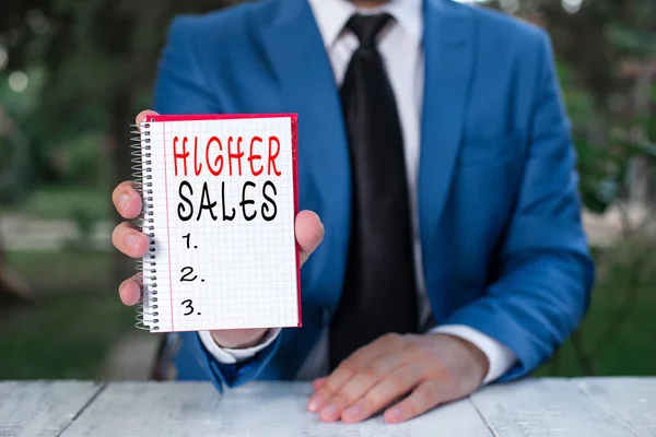 A magasabb eladások szöveget mutató szöveges jel. Fogalmi fotó az átlagos eladott termékek és szolgáltatások a vállalat nőtt férfi rendelkezik üres papírt másolási tér előtte. — Stock Fotó