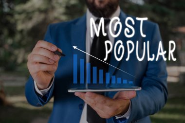 Kelime yazma metni En Popüler. Bir toplumda gösteren çoğunluğu tarafından Zevk Sevdim için İş konsepti Erkek giyim resmi iş elbisesi akıllı cihaz kullanarak sunum sunan.