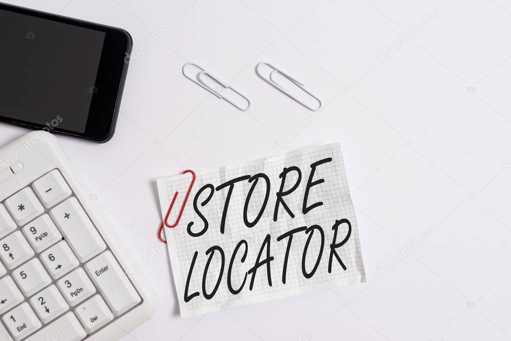 Text sign showing Store Locator. Conceptual photo to know the address contact number and operating hours White pc keyboard with empty note paper above white background and mobile phone.