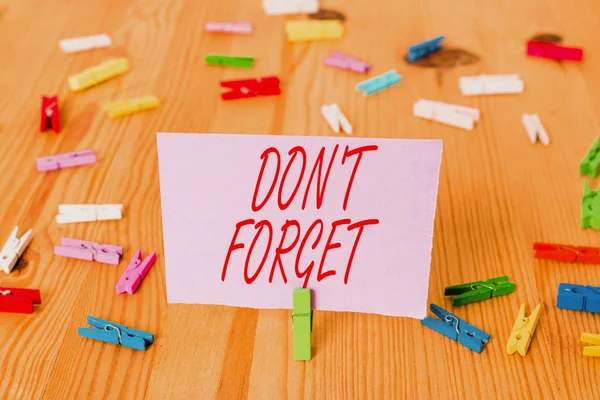 Handwriting text Don T Forget. Concept meaning Know by Heart Think Back Fix in the Mind Refresh Memory Colored clothespin papers empty reminder wooden floor background office.