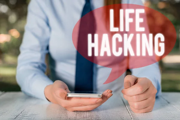 Writing note showing Life Hacking. Business photo showcasing Simple and clever techniques in accomplishing task easily Female business person sitting by table and holding mobile phone.