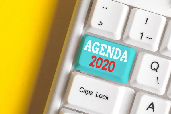 Writing note showing Agenda 2020. Business photo showcasing list of activities in order which they are to be taken up White pc keyboard with note paper above the white background. — Stock Photo, Image