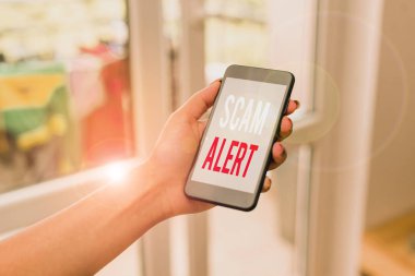 El yazısı metin yazma Scam Alert. Kavram düzeni veya dolandırıcılık hakkında birisi uyarı haber akıllı telefon ofis malzemeleri ev içinde teknolojik cihazlar kullanarak herhangi bir sıradışı kadın.