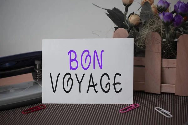 Szöveges jel mutatja Bon Voyage. Fogalmi fotó használt kifejezni jókívánságait, hogy valaki elindult az utazás virágok és írásban berendezések, valamint sima lap felett textúrázott hátteret. — Stock Fotó