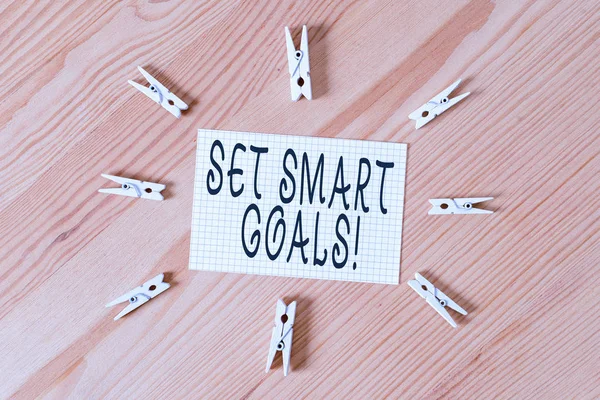 Conceptual hand writing showing Set Smart Goals. Business photo text list to clarify your ideas focus efforts use time wisely Colored crumpled papers wooden floor background clothespin.