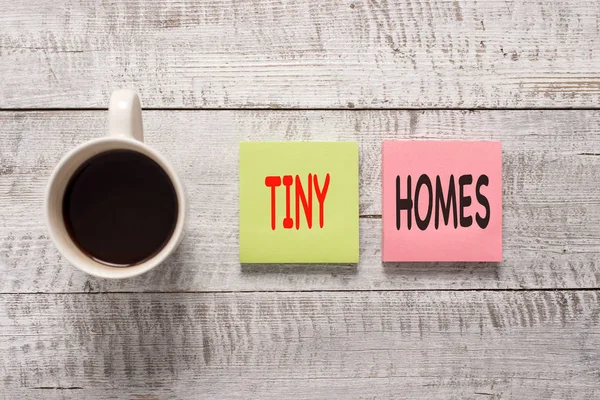Handwriting text writing Tiny Homes. Concept meaning houses contain one room only or two and small entrance Cheap Stationary placed next to a cup of black coffee above the wooden table.