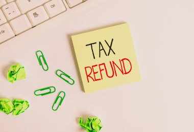 Handwriting text Tax Refund. Concept meaning applied when money liability is less than the paid ones Square empty green note paper with pencil on the white background and pc keyboard. clipart