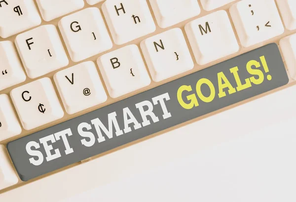Conceptual hand writing showing Set Smart Goals. Business photo text list to clarify your ideas focus efforts use time wisely White pc keyboard with note paper above the white background.