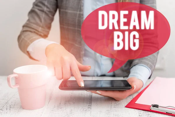 Text skylt som visar Dream Big. Konceptuell bild att tänka på något högt värde som du vill uppnå affärskvinna sitter med mobiltelefon och kopp kaffe på bordet. — Stockfoto