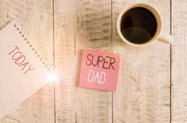 Conceptual hand writing showing Super Dad. Business photo text Children idol and super hero an inspiration to look upon to Stationary placed next to a coffee cup above wooden table.