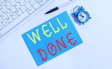 İyi Bitti'yi gösteren bir not yazıyorum. Peform'u doğru ve özenle becerive verimli bir şekilde düz bir şekilde sergileyen iş fotoğrafı, pc klavyesi kalemleri ve saati üzerindeki boş not kağıdının üzerinde yatıyordu.