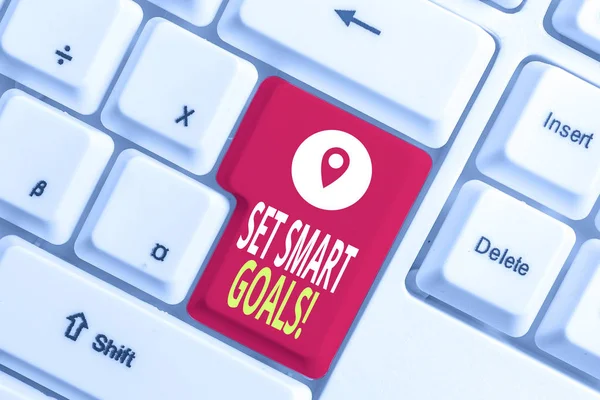 Writing note showing Set Smart Goals. Business photo showcasing list to clarify your ideas focus efforts use time wisely White pc keyboard with note paper above the white background.