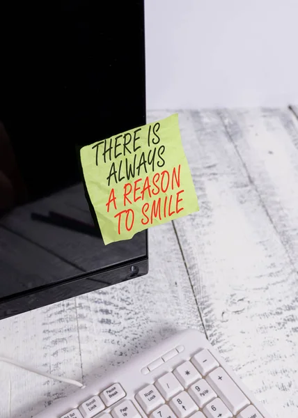 Woord tekst schrijven er is altijd een reden om te glimlachen. Business concept voor positief denken goede houding energie notatie papier geplakt naar zwarte computer monitor scherm in de buurt van wit toetsenbord. — Stockfoto