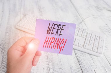 İşe Aldığımızı gösteren bir metin işareti. Kavramsal fotoğraf son zamanlarda birini istihdam veya renkli hatırlatma kare şeklinde kağıt beyaz klavye ahşap zemin tutan belirli bir iş adam yapmak için birisi ödemek.