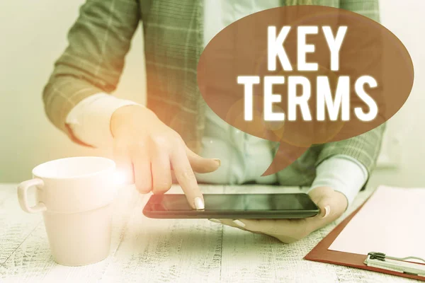 Text sign showing Key Terms. Conceptual photo Words that can help a demonstrating in searching information they need Business woman sitting with mobile phone and cup of coffee on the table.