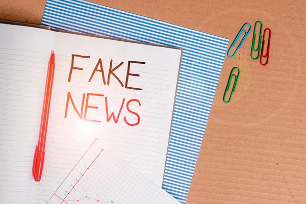 Notizen, die Fake News zeigen. Geschäftsfotos, auf denen zu sehen ist, dass die Medien gestreiftes Notizbuch aus Pappe zeigen, Bürostudie liefert Diagrammpapier. — Stockfoto