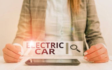 Electric Car 'ın el yazısı. Bir ya da daha fazla elektrik motoru tarafından itilen bir otomobil anlamına gelen kavram. Masada cep telefonu olan bir iş kadını oturuyor..
