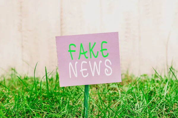 Notizen, die Fake News zeigen. Business-Foto, das Informationen zu zeigen, dass nicht wahr ist, indem die Medien einfaches Papier am Stick befestigt und im Grasland platziert. — Stockfoto
