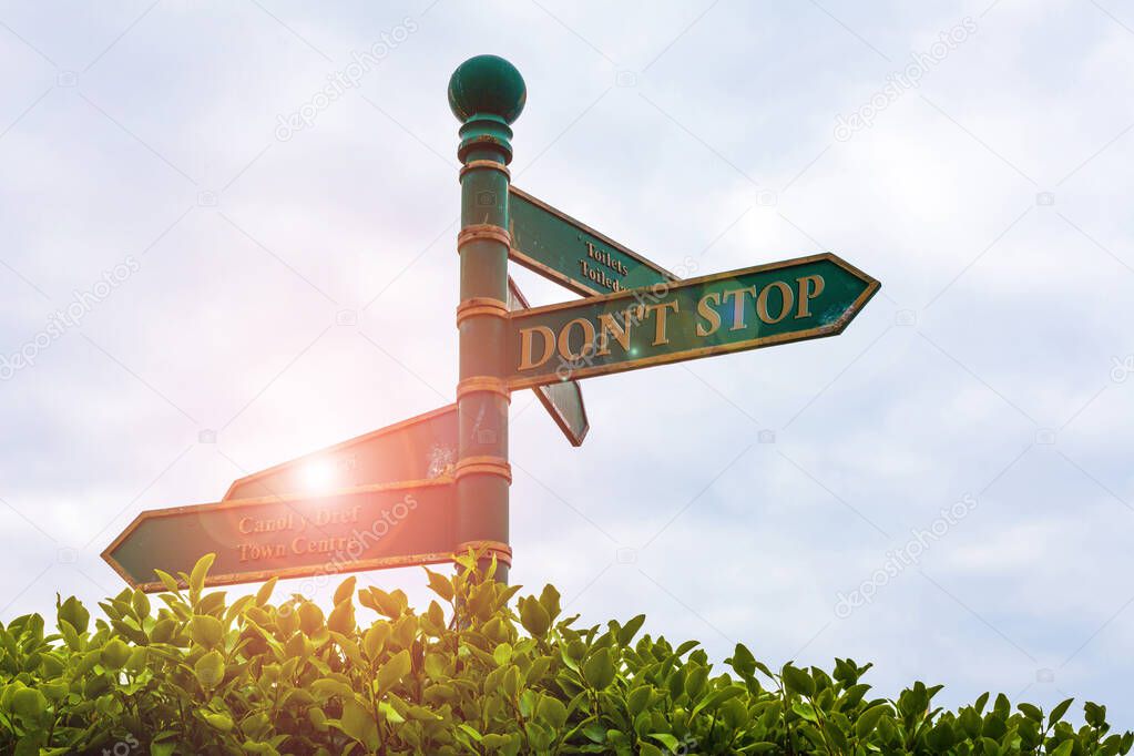 Text sign showing Don T Stop. Conceptual photo Continue what had been doing without rendering a delay Green road sign on the crossroads with cloudy sky and green grass in the background.