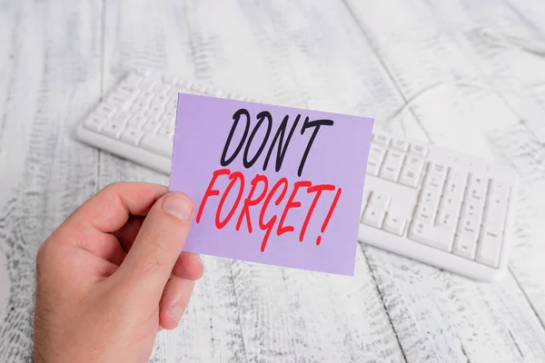 Tekst teken weergeven van Don T vergeten. Conceptuele foto gebruikt om iemand te herinneren over belangrijk feit of detail man Holding kleurrijke herinnering vierkant gevormde papier wit toetsenbord houten vloer. — Stockfoto