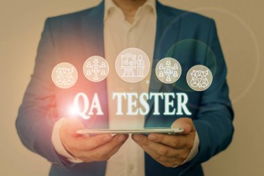 Qa Testçisini gösteren bir not yazıyorum. Uygulamadan önce devam eden bir projenin iş fotoğrafının Kalite Güvencesini göstermek için Erkek, sunum akıllı aygıtı sunan resmi iş elbisesi giyer.