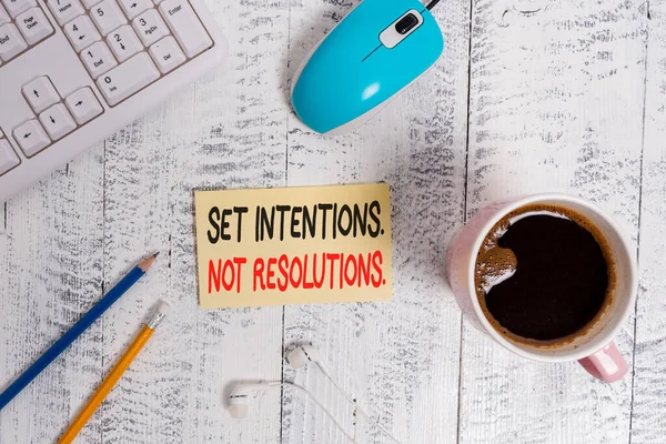 Conceptual hand writing showing Set Intentions Not Resolutions. Business photo text Positive choices for new start achieve goals Technological devices colored reminder paper office supplies.