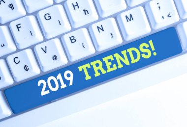 2019 Trendlerini gösteren kavramsal el yazısı. Bir şeyin beyaz arka plan üzerinde not kağıdı yla Beyaz bilgisayar klavyesi geliştirdiği veya değiştirdiği iş fotoğrafı metni genel yönü.