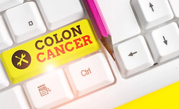 Handwriting text Colon Cancer. Concept meaning the development of cancer cells from the colon or rectum White pc keyboard with empty note paper above white background key copy space.
