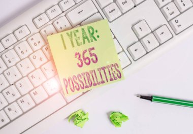1 yıl 365 olasılığı gösteren bir not yazıyorum. Yeni bir günün başlangıcını gösteren iş fotoğrafı beyaz arkaplan ve klavyede kurşun kalemle yeşil not kağıdını başlatmak için bir sürü şans.