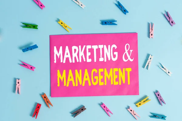 Conceptual hand writing showing Marketing And Management. Business photo showcasing process of developing strategies for product Colored clothespin rectangle shaped paper blue background. — 图库照片