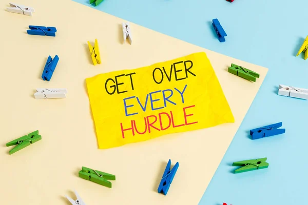 Handwriting text writing Get Over Every Hurdle. Concept meaning Overcome any obstacle problem trouble adversities Colored clothespin paper empty reminder yellow blue floor background office.