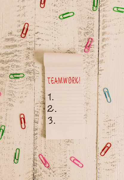 Text sign showing Teamwork. Conceptual photo combined action of group especially when effective and efficient Stripped ruled notepad clips lying wooden old retro vintage background.