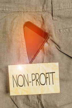Non Profit 'i gösteren bir not yazıyorum. İş fotoğraflarının sergilendiği bir organizasyon. Pantolonun içindeki akıllı telefon cihazından kar elde edemiyorlar. Ön cebinde kağıt var..