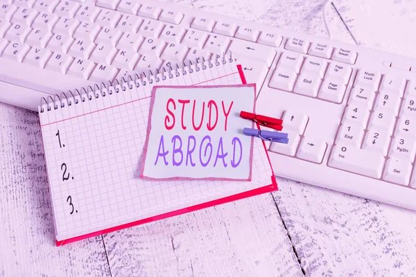 Conceptual hand writing showing Study Abroad. Business photo showcasing live in a foreign country and attend a foreign university notebook reminder clothespin with pinned sheet light wooden.