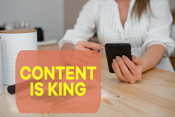 Writing note showing Content Is King. Business photo showcasing believe that content is central to the success of a website woman using smartphone and technological devices inside the home.