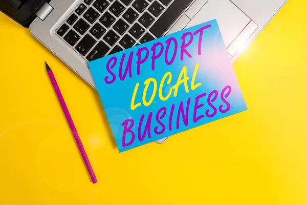 サポートローカルビジネスを示す概念的な手書き。あなたの国や町への投資を増加させるビジネス写真金属ラップトップの小さな紙のシート鉛筆色の背景. — ストック写真
