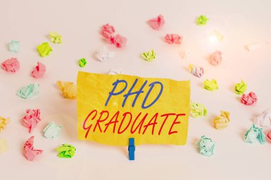 Kelime yazma doktorası derecesi. Bir dersten sonra verilen en yüksek üniversite diploması konsepti. Renkli buruşmuş kağıtlar boş hatırlatıcı beyaz zemin çamaşır mandalı..