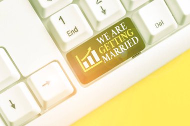 Kavramsal el yazısı evlendiğimizi gösteriyor. İş fotoğrafı metni, nişan hazırlığı, beyaz arkaplanının üstünde nota kağıdı olan beyaz bilgisayar klavyesini seven çift..