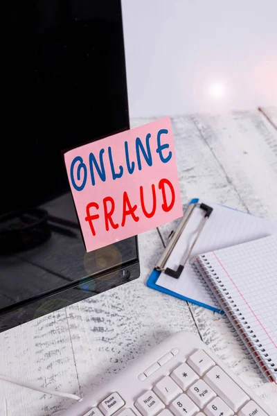 Writing note showing Online Fraud. Business photo showcasing use of Internet services to deceive victims and steal money Note paper taped to black computer screen near keyboard and stationary.